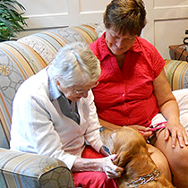 A volunteer and a resident playing with a dog